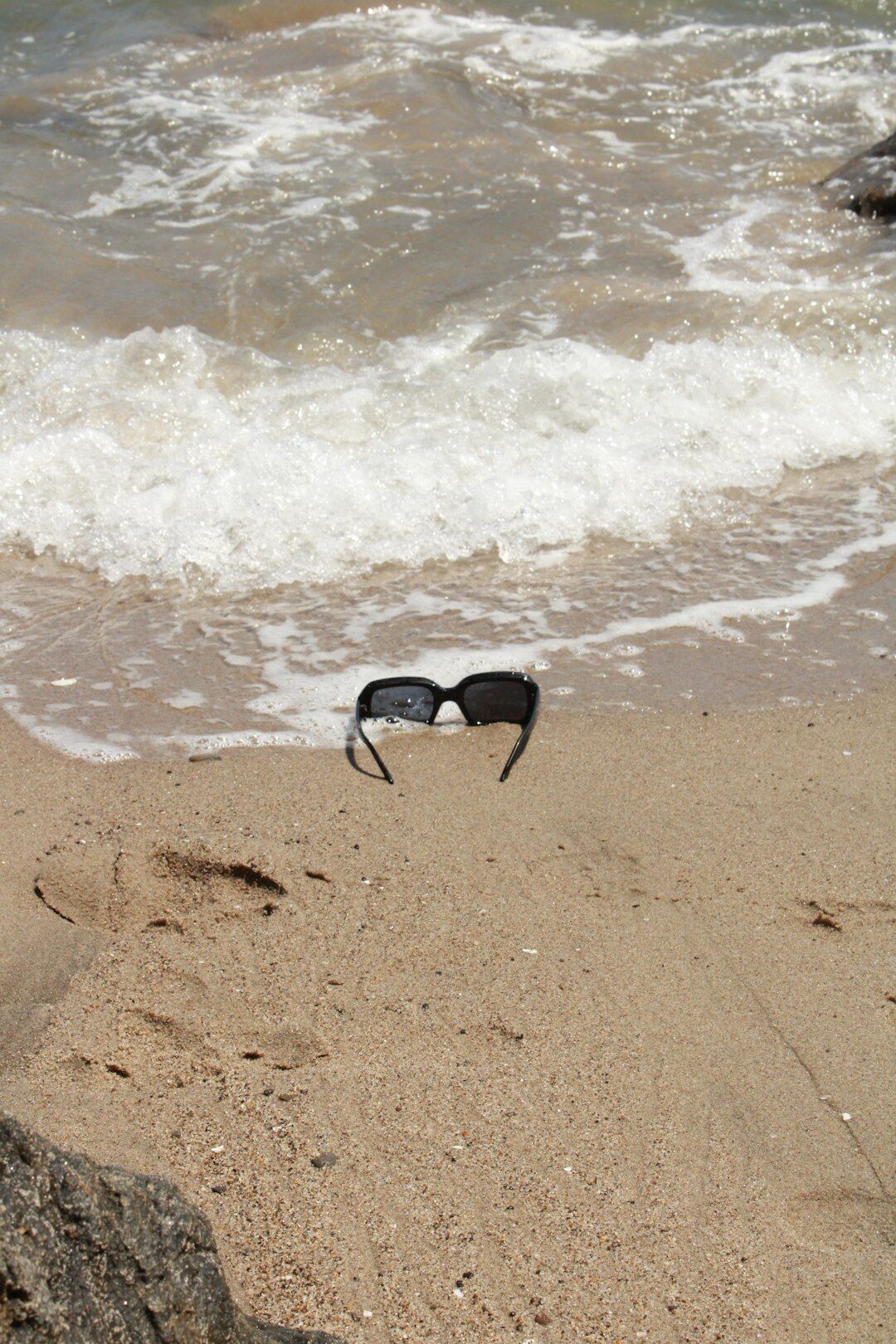 Polarized aviator sunglasses on sand near the shoreline